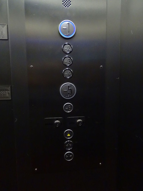 Buttons, top down with numbers from minus 1 to minus 6, on a control panel of an elevator.